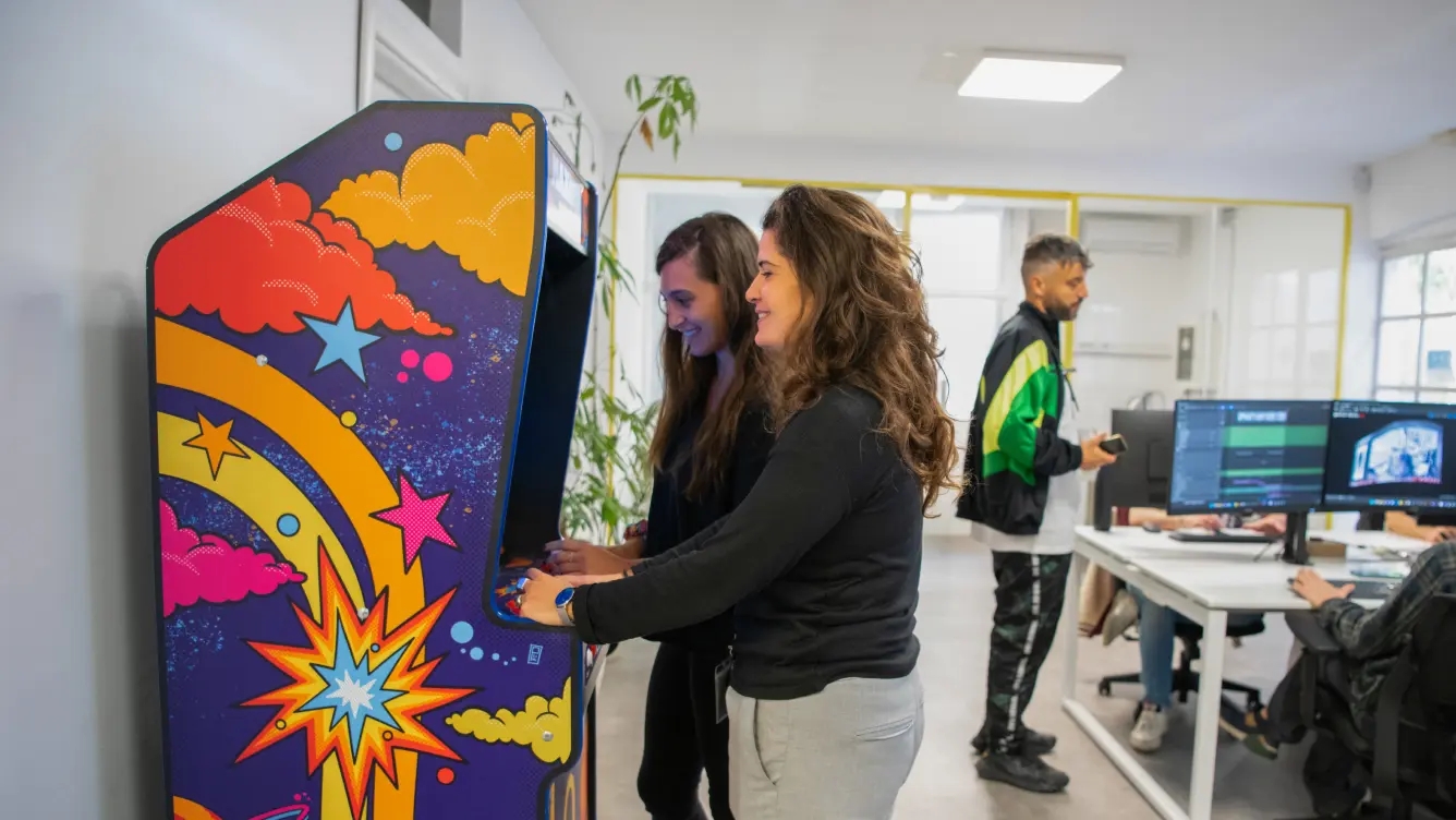 Workplace with girls playing coin-operated games and a boy conversing with colleagues